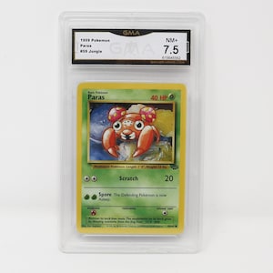 Peut inclure: Une carte à jouer Pokemon représentant Paras, un Pokemon champignon avec un corps rouge et orange et un fond jaune. La carte est classée NM+ 7.5 par GMA Grading. Le texte de la carte indique "Pokemon de base Paras 40 PV" et "Pokemon champignon. Longueur : 1'0", Poids : 12 lbs."