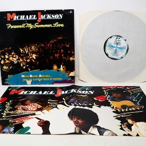 May include: A Michael Jackson "Farewell My Summer Love" album. The album cover is black with the title in yellow and red. The album is open, revealing the record and inner sleeve. The album art features a crowd and images of Michael Jackson.