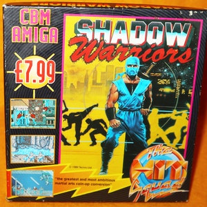 Könnte beinhalten: Eine Schachtel für das Amiga-Videospiel Shadow Warriors. Die Schachtel ist gelb und schwarz mit einem Bild eines blauen Ninjas auf der Vorderseite. Das Spiel kostet 7,99 £. Der Text auf der Schachtel lautet "Die größte und ehrgeizigste Umwandlung von Kampfspielen aus der Spielhalle."