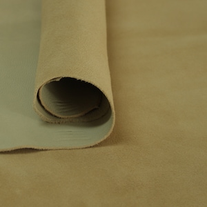 Puede incluir: Un rollo de cuero marrón claro. El cuero es suave y flexible, con una superficie ligeramente texturizada.