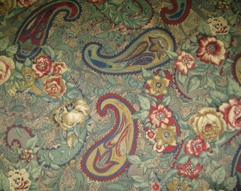 May include: A paisley patterned fabric with a green, brown, and blue color scheme. The fabric features a floral design with red, yellow, and white flowers.