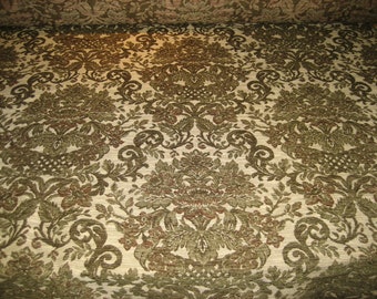 May include: A close-up of a fabric with a damask pattern in shades of green and brown on a cream background.