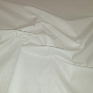 May include: White fabric with a smooth, silky texture. The fabric is folded and draped, creating soft folds and curves.