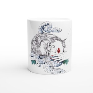Pode incluir: Uma caneca de cerâmica branca com uma ilustração detalhada de linhas a preto e branco de uma pessoa com cabelo ondulado, rodeada por duas cobras. A pessoa tem lábios vermelho-brilhantes e unhas vermelhas, com pequenas folhas verdes.