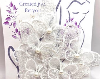 May include: White lace veil weights in a floral design, each with a pearl center. The card reads "Veil Weights" in purple text. The weights are designed to keep a veil in place.