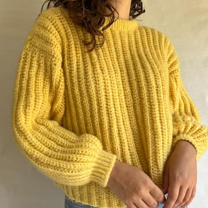 May include: A yellow knitted sweater with a ribbed texture and puffed sleeves.