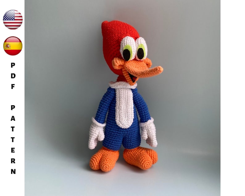 May include: A handmade crochet Woody Woodpecker doll. The cartoon character is depicted with a red head, orange beak and feet, blue body, white gloves and collar. The doll is standing against a light gray background. The text "PDF PATTERN" is on the left side of the image.