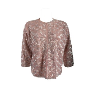 May include: A pink sequined jacket with a zip closure. The jacket has a subtle pattern of small, silver sequins.