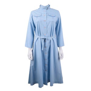 May include: A pale blue dress with a button-down front, a collared neckline, and a matching belt. The dress has two chest pockets and three-quarter sleeves. The dress is approximately 122 cm long.