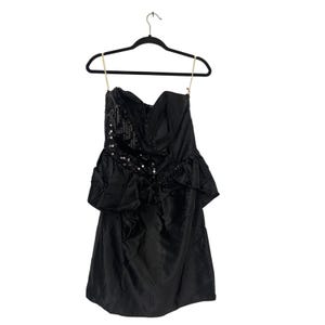 May include: A black strapless dress with a sweetheart neckline and a sequined bodice. The dress features a ruffled peplum and is hanging on a black hanger. The dress is made of a shiny fabric.