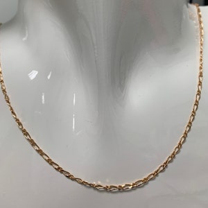 Op de afbeelding: Een gouden ketting met een delicate figaro-stijl ketting. De ketting is op een wit mannequin.