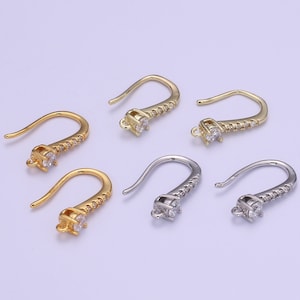 May include: Six earring hooks with a clear rhinestone at the top and a row of smaller rhinestones along the hook. The hooks are available in gold and silver.