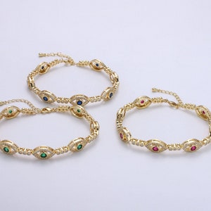May include: Three gold bracelets with a chain link design and an evil eye charm. The charms are set with small clear stones and a single colored stone in the center. The bracelets feature blue, green, and red stones.
