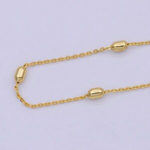 May include: A gold chain necklace with small oval-shaped beads.