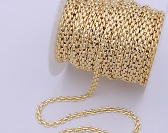 May include: A spool of gold-colored chain, with a portion of the chain uncoiled and lying on a white surface.
