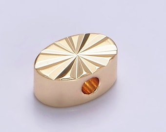 May include: A gold oval-shaped bead with a starburst design and a hole in the center.