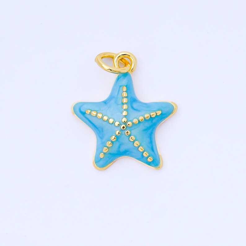 May include: A light blue starfish pendant with gold-colored accents. The five-pointed star has a gold outline and is decorated with small gold dots. The pendant has a gold loop for attaching to a chain or bracelet.