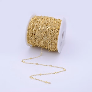 May include: A spool of gold-colored chain with a square link pattern. The chain is wound around a white spool.