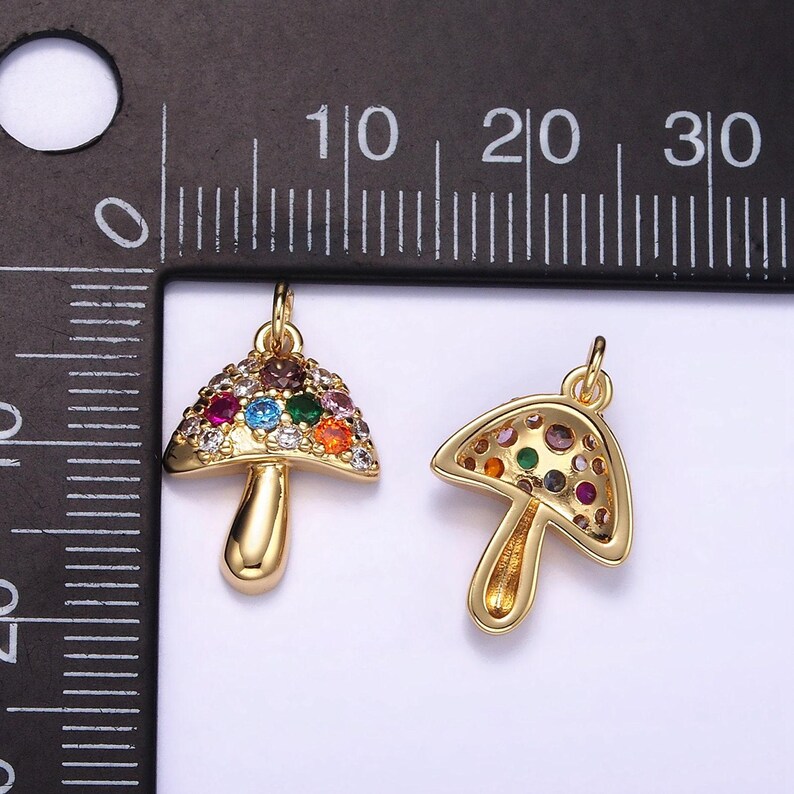May include: Two gold-tone mushroom charms with colorful crystal accents. The charms are approximately 1 inch in size.
