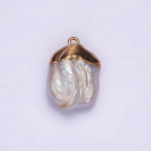 May include: A large, white baroque pearl pendant with a gold cap. The pearl has an irregular shape and a smooth, iridescent surface.