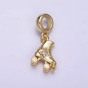 May include: Gold-toned roller skate charm with clear crystal accents. The charm has a loop at the top for attaching to a bracelet or necklace.