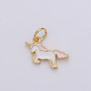 May include: A gold-colored unicorn charm with white enamel body and pink mane and tail. The charm has a loop at the top for attaching to a necklace or bracelet. The unicorn is a popular fantasy symbol.