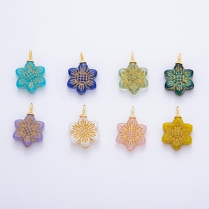 May include: Eight colorful flower-shaped pendants with gold-colored bails. The pendants are in shades of blue, green, purple, pink, and yellow. Each pendant has a detailed floral design in a contrasting color. These pendants are ideal for jewelry making.