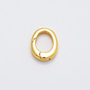 May include: A gold-colored oval clasp, featuring a hinged design for secure closure. The clasp has a smooth, polished surface, reflecting light. The design is simple and elegant, suitable for jewelry or accessories.