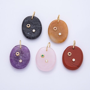 May include: Five gemstone pendants in black, brown, purple, pink, and red. Each has a gold bail and two inset gemstones, one coloured and one clear, round-cut stone. Ideal for necklaces.