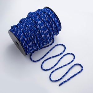 May include: A spool of blue rope with a white reflective pattern. The rope is coiled on a black spool, with a length of rope unraveled and laid out in a wavy pattern. The rope is suitable for various crafting and outdoor projects.
