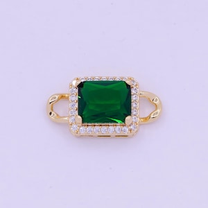 Pode incluir: Pingente dourado com uma gema verde quadrada cercada por pedras de zircônia cúbica transparentes.