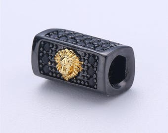 May include: Black and gold lion head charm with black cubic zirconia stones. The charm is rectangular and has a hole for attaching to a bracelet or necklace.