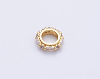 May include: A gold-colored, circular bead with a central hole. The bead is adorned with clear, rectangular-cut gemstones around its outer edge. The design is symmetrical and suitable for jewelry making.