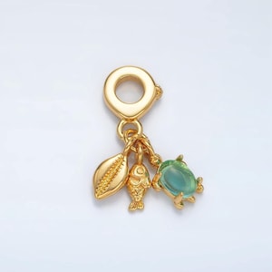 May include: Gold charm with a seashell, fish, and crab design. The crab has a light blue gemstone.