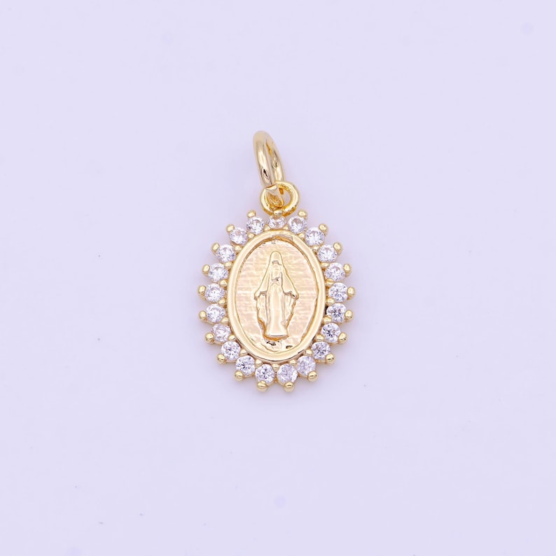May include: Gold-toned pendant featuring a depiction of the Virgin Mary within an oval frame surrounded by clear cubic zirconia stones.