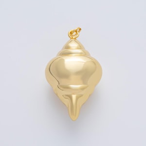 May include: A polished gold-colored pendant in the shape of a conch shell. The pendant has a smooth, reflective surface and a small loop at the top for a chain. The shell design features a spiral pattern and a pointed base.