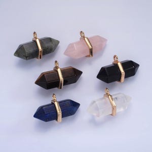 May include: Six double-terminated crystal point pendants with gold-toned metal caps. The crystals are in various colors, including black, clear, pink, blue, brown, and gray.