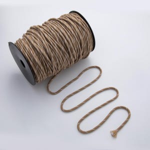 May include: A spool of tan and white patterned rope sits next to a length of the same rope. The rope is wound around a black plastic spool. The rope has a textured appearance and is suitable for various crafting and DIY projects.