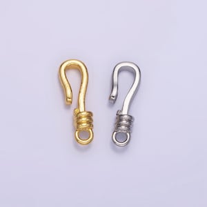 May include: Two metal clasps, one gold and one silver, with a coiled spring design. The clasps are used for attaching jewelry or other items.