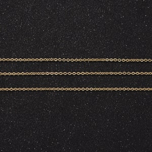 May include: Three gold chains on a black sparkly background.