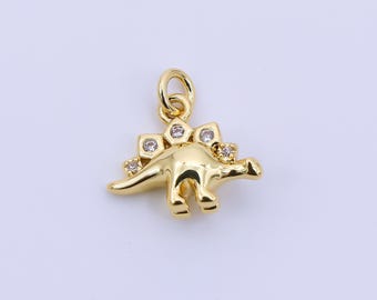 May include: A gold-colored dinosaur charm with a loop for hanging. The charm features a stegosaurus design with small, clear gemstones on its back plates. The dinosaur is facing left.