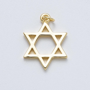 Puede incluir: Un colgante dorado con forma de Estrella de David con un pequeño lazo en la parte superior para una cadena. El colgante es una estrella de seis puntas con un centro hueco, probablemente de metal.