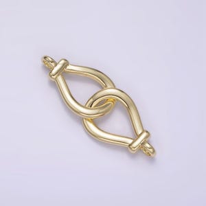 May include: Gold-toned metal connector with a teardrop shape. The connector is made of two interlocking loops.