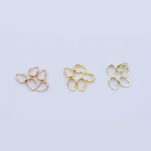 May include: Six gold, six rose gold, and six silver oval-shaped jump rings. The jump rings are arranged in three groups of six, with each group in a different colour.