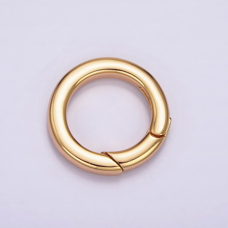 Pode incluir: Anel de metal dourado com fecho de mola. O anel &eacute; liso e brilhante.