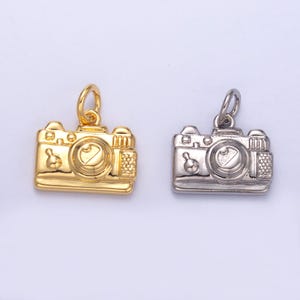 May include: Two camera charms, one gold and one silver, with a detailed design. The charms are perfect for adding a touch of personality to necklaces, bracelets, or keychains.