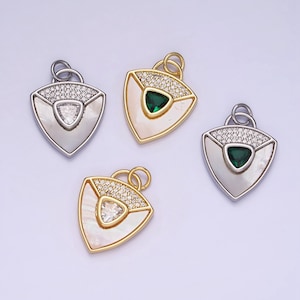 May include: Four pendant charms in silver and gold tones. Each charm has a triangular shape with a mother-of-pearl inlay, a central gemstone, and a border of small, clear crystals. The charms are designed for jewelry making.