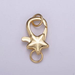 May include: Gold-toned metal star-shaped clasp with a ring for attaching to a necklace or bracelet.