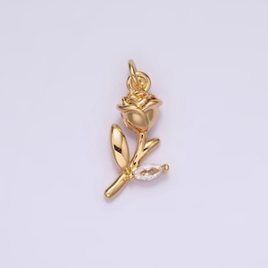 May include: Gold-tone rose charm with a clear rhinestone accent. The rose is detailed with a stem and leaf.