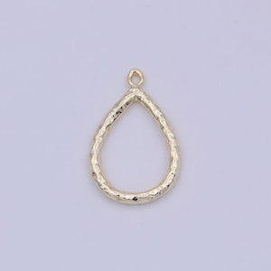 May include: Gold teardrop shaped pendant with a textured surface. The pendant has a loop at the top for attaching to a chain or cord.